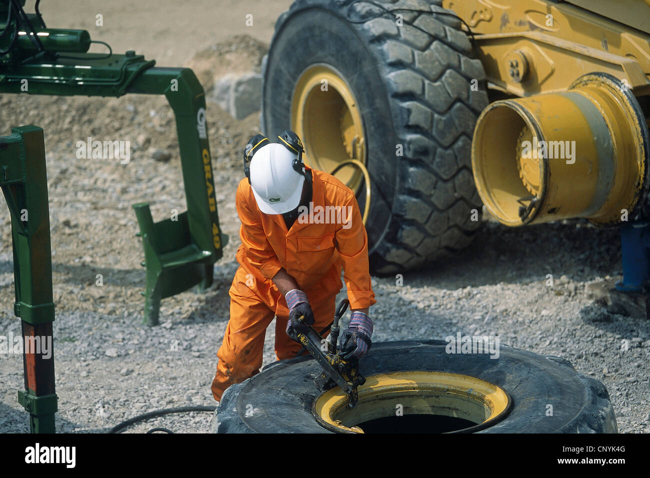 Mechanic changing tyre on heavy duty articulated dumper truck. Stock Photo