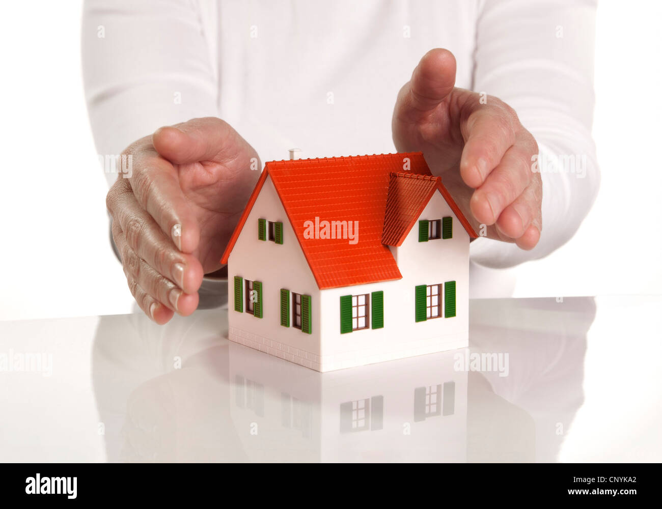 Hands protectively cover an architectural model. Stock Photo