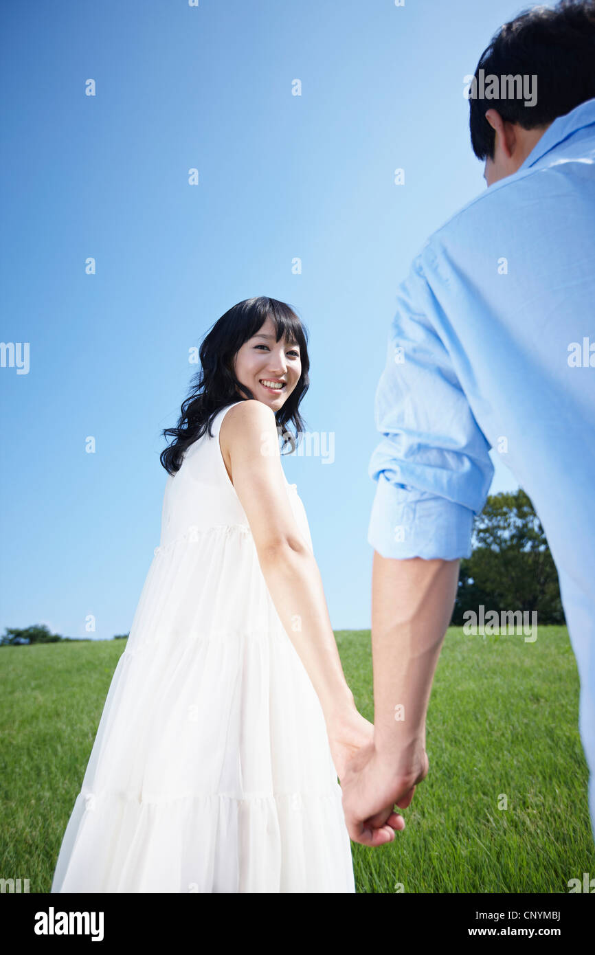 A couple holding hands in green field Stock Photo - Alamy