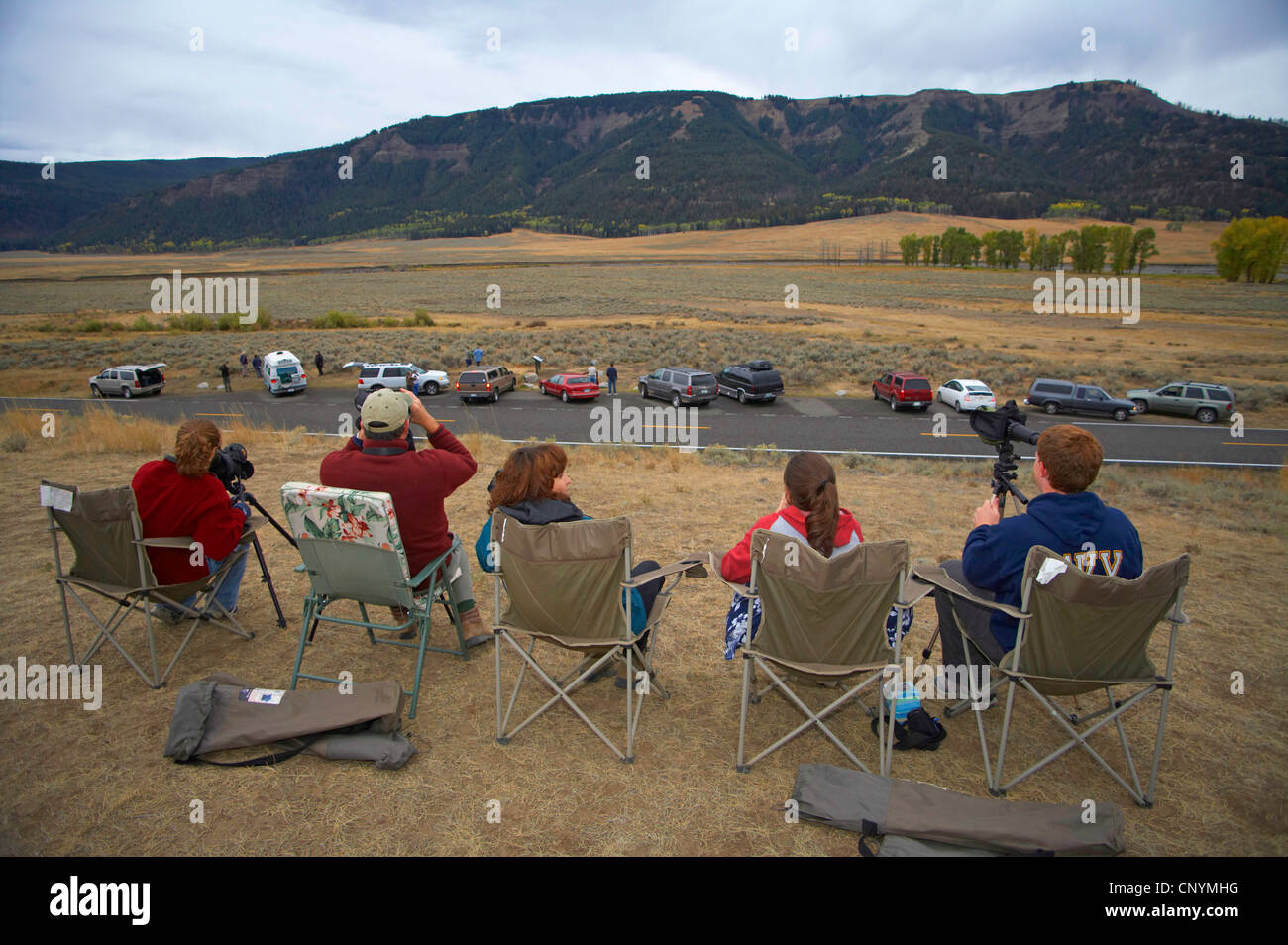 wolf watchers sitting in folding chairs looking out over a valley, USA, Yellowstone National Park, USA, Wyoming Stock Photo