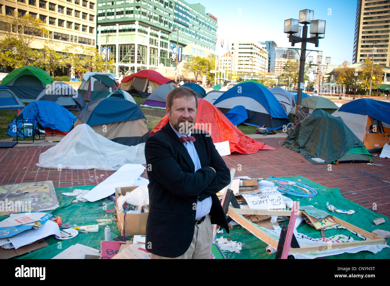 Man stands in jest against occupy movement tents in Baltimore, MD Stock Photo