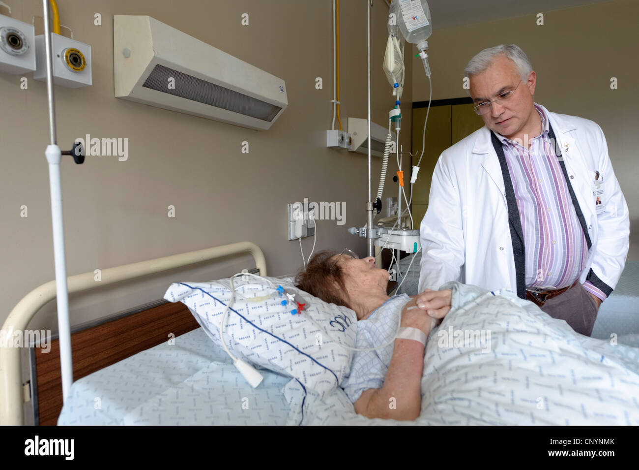 Doctor next to patient's bed in hospital ward Stock Photo