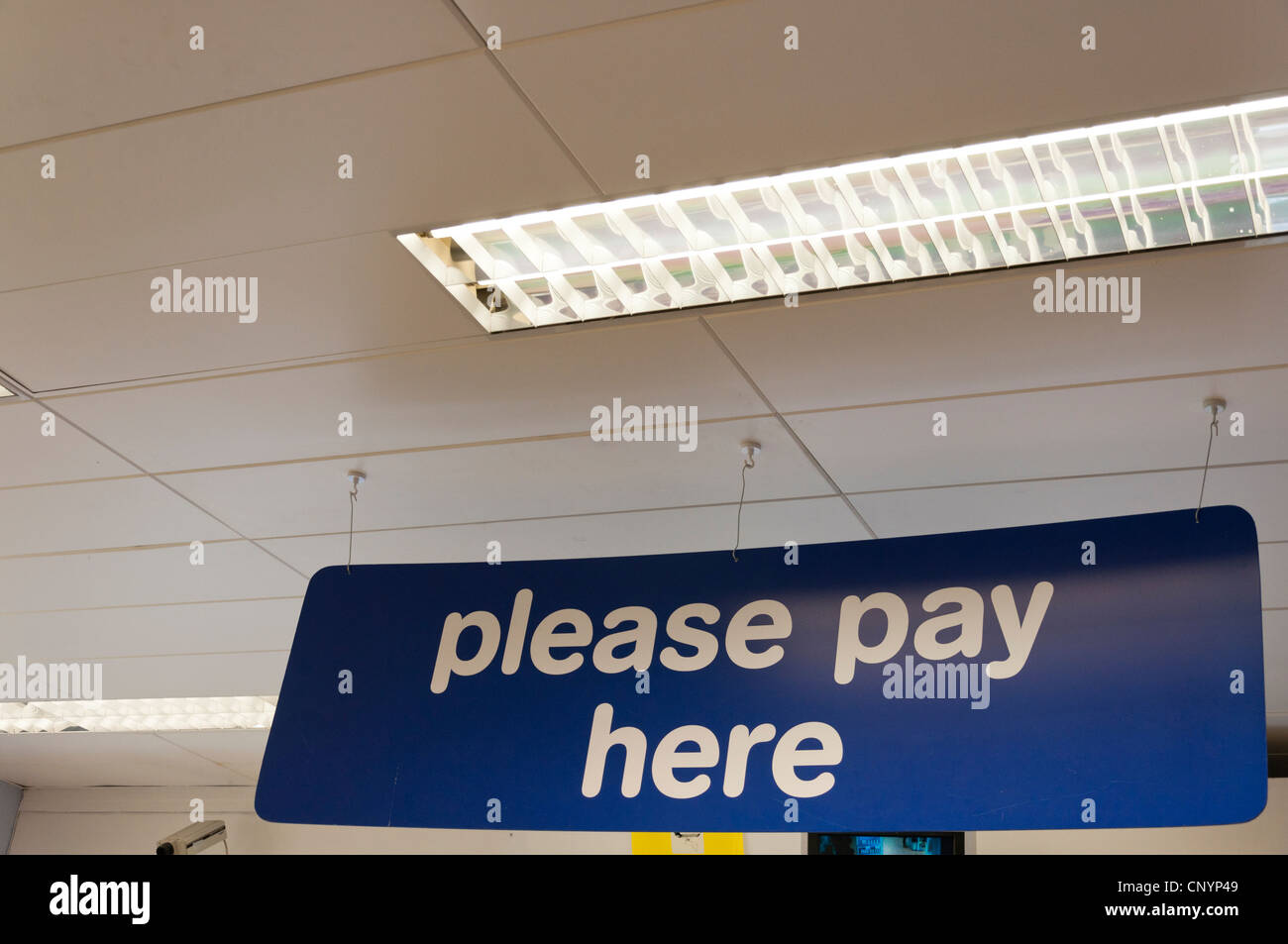 Please pay here sign hanging from the ceiling of a shop. Stock Photo
