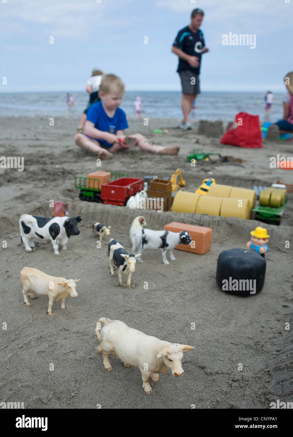 Child playing on Carnlough beach with model farm animals. Stock Photo
