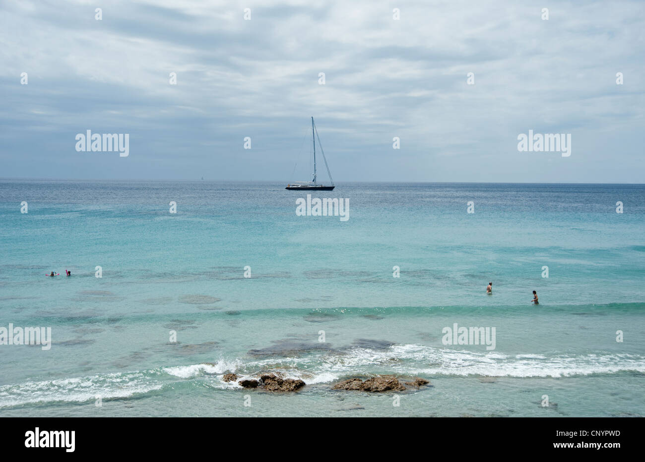 A luxury yacht sails past Binigaus beach Menorca Spain Stock Photo