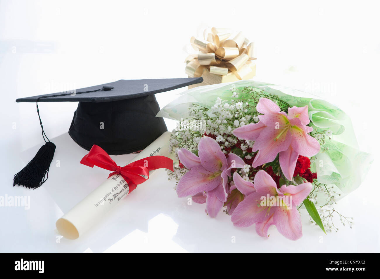 The graduation cap, the diploma, and the bouquet of flower Stock Photo
