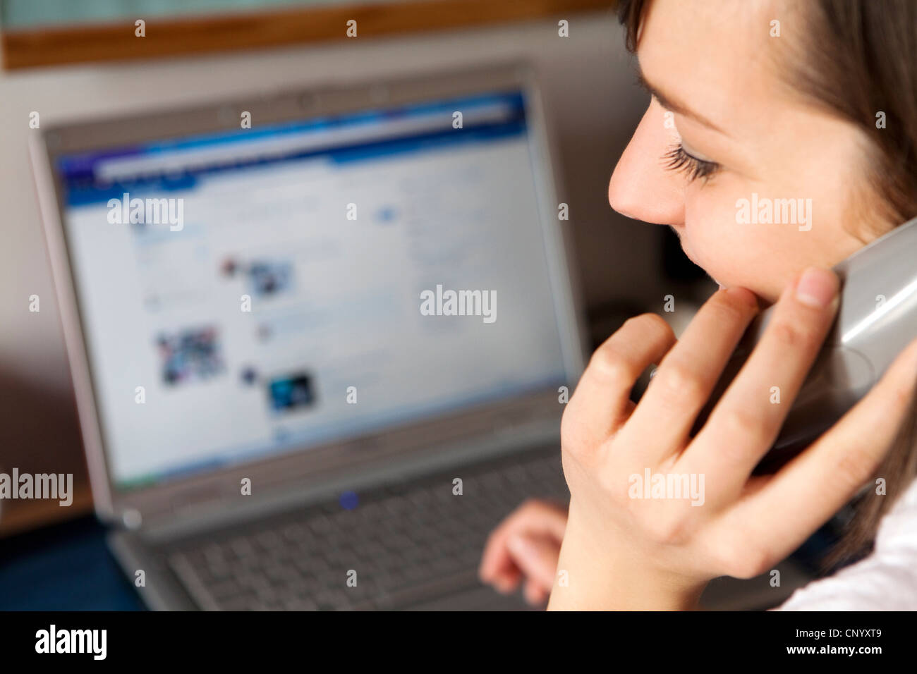 a woman on the phone in front of to computer,facebook Stock Photo