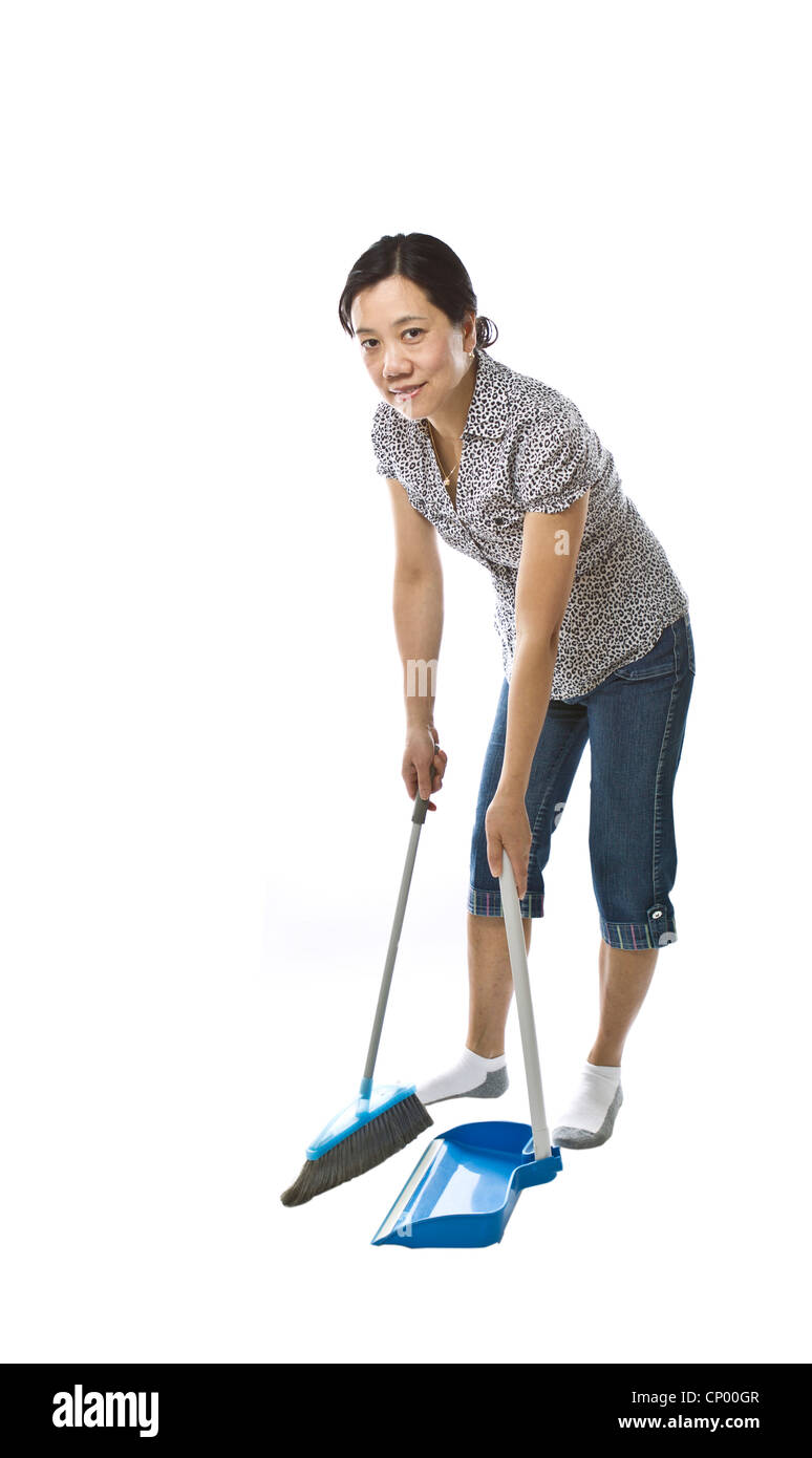 Asian lady with broom and dust pan while wearing causal clothing on white background Stock Photo