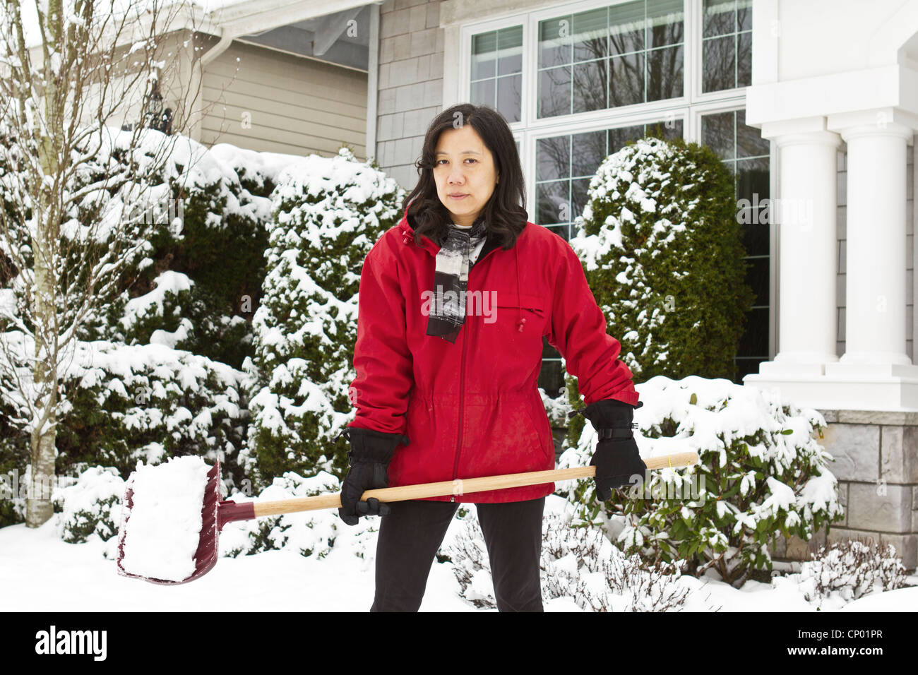 Women working outside cleaning snow in front of house Stock Photo