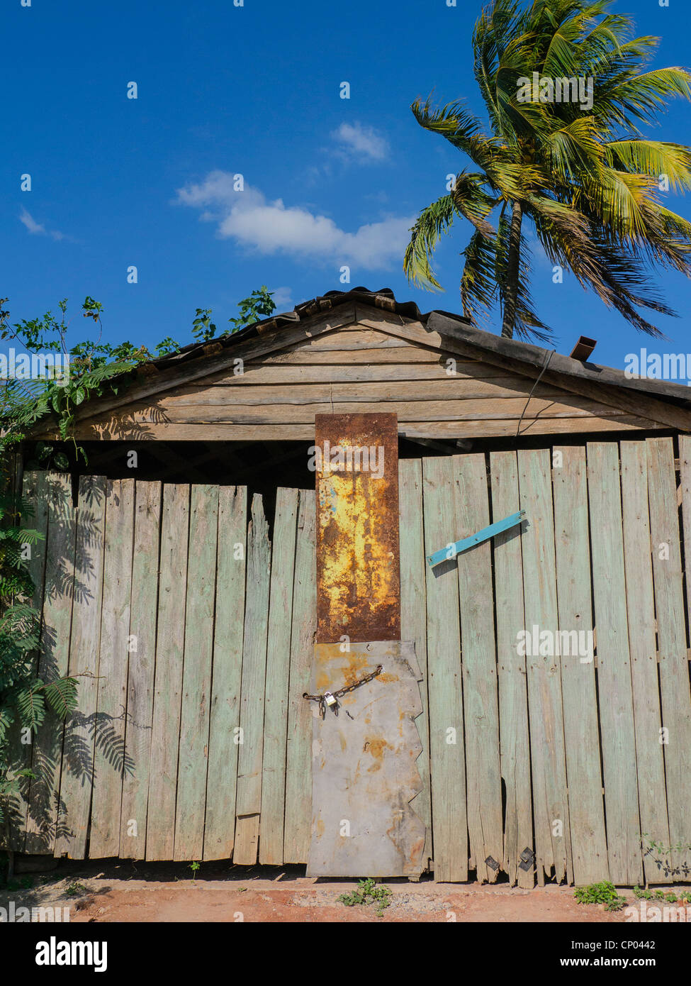 The front entrance of a dilapidated wooden garage with the doors rigged closed with sheet metal and a lock in Viñales, Cuba. Stock Photo