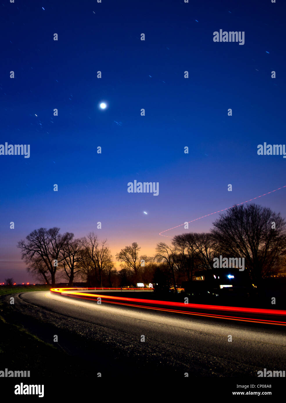A car and plane making a curve at night under the stars and Venus. Stock Photo
