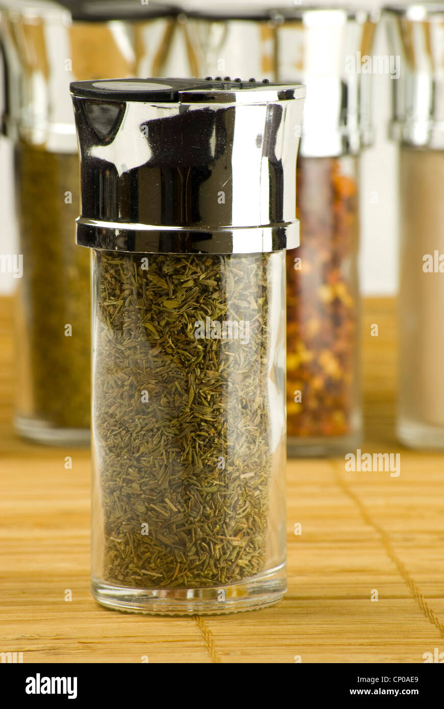 dried thyme in a glass jar on different spices background over wooden