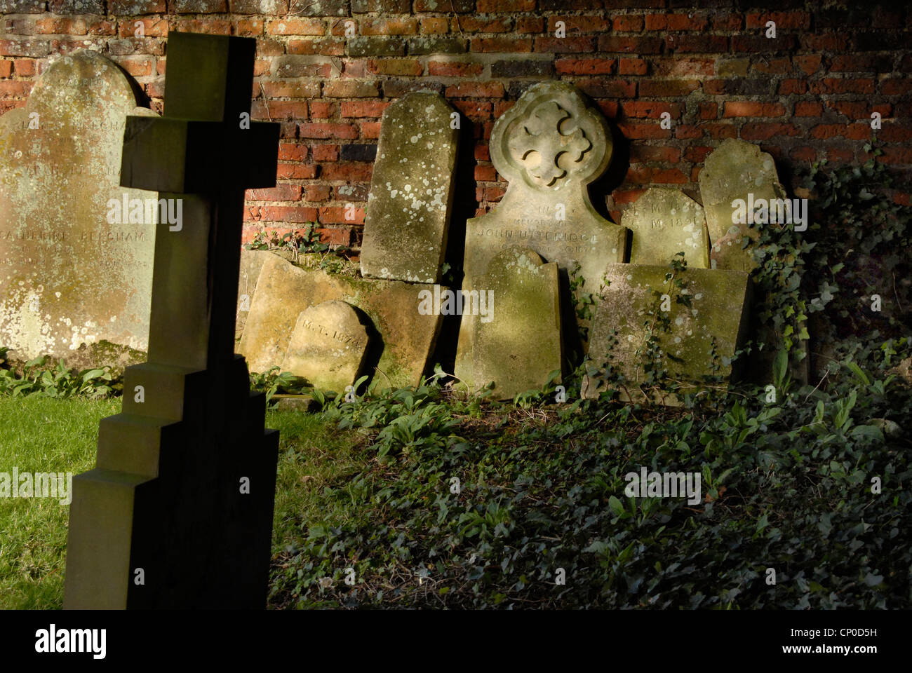 The graveyard of St Andrew and St Mary's Church in Grantchester  Cambridgeshire, with old headstones  stacked against the wall. Stock Photo