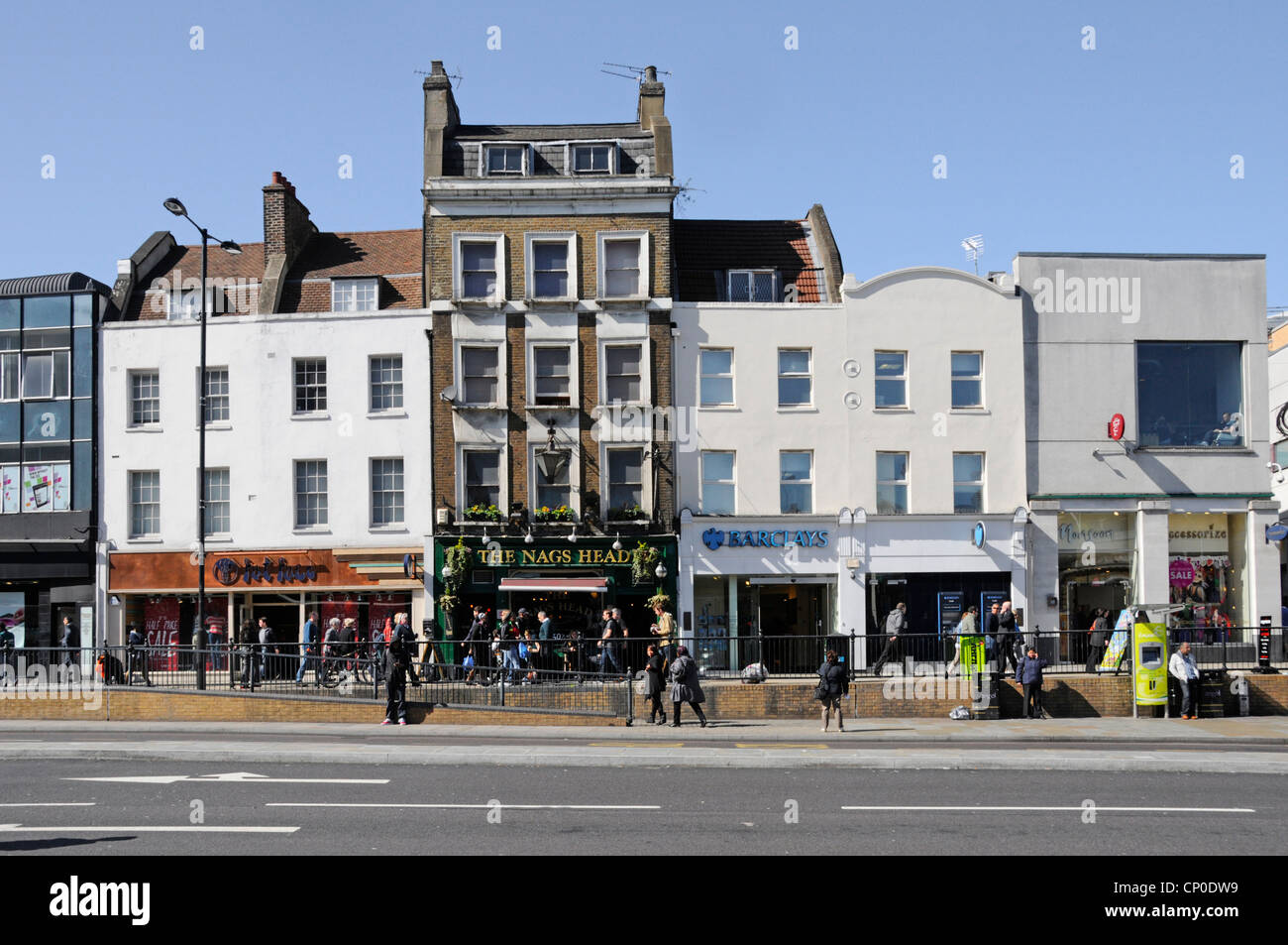 People in Upper Street sunny winter scene including retail shops The Nags Head pub & business premises Islington London England UK Stock Photo