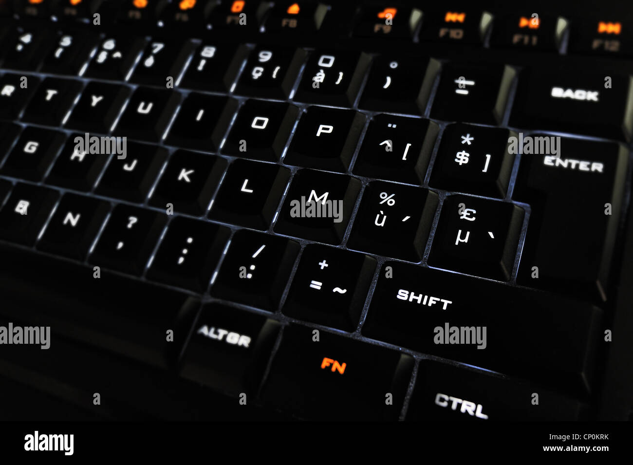 Black computer keyboard with illuminated backlit white characters on keys in the dark Stock Photo