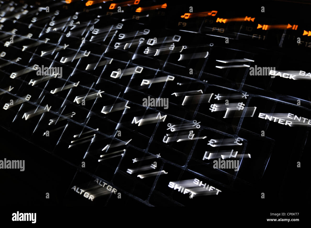 Abstract technology image showing black computer keyboard with illuminated backlit white characters on keys jumping out Stock Photo