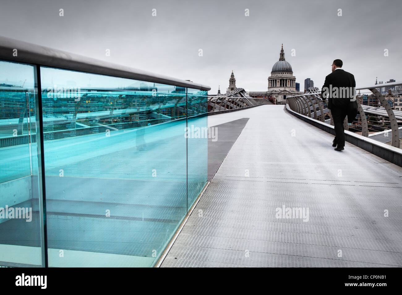 A commuter crossing millennium bridge in London. Stock Photo