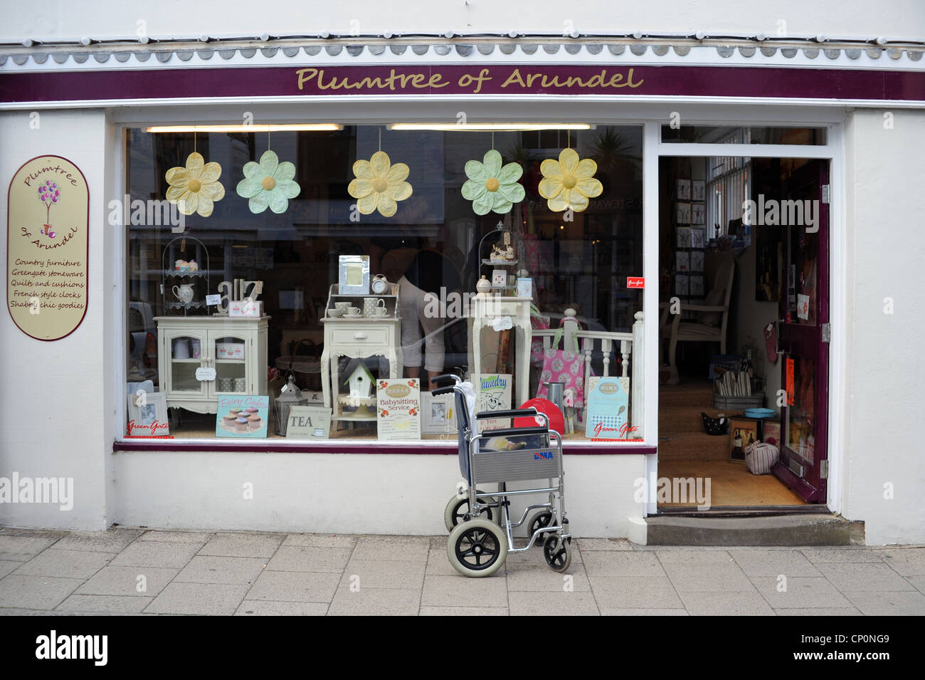 A wheel chair parked outside the shop Plumtree of Arundel, West Sussex Stock Photo