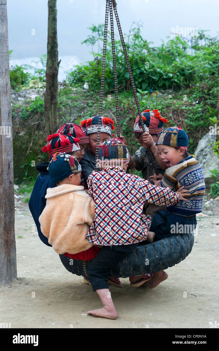 Children from the Red Hmong ethnic group, playing on a swing made for a  tyre at a village near Sapa, Viet Nam Stock Photo - Alamy