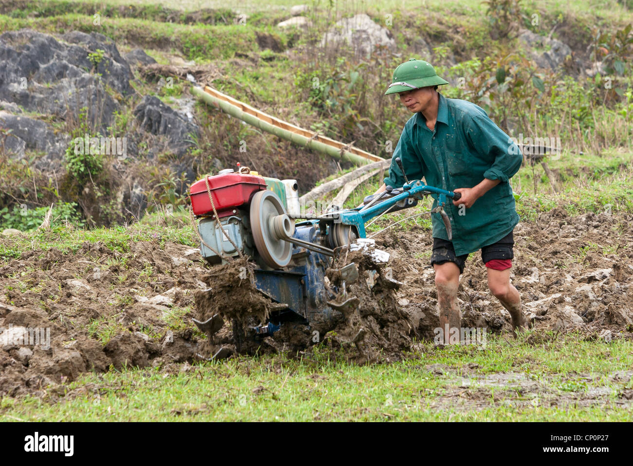A young farmer tilling his field using a petrol-driven rotary tiller instead of an ox plough. Stock Photo