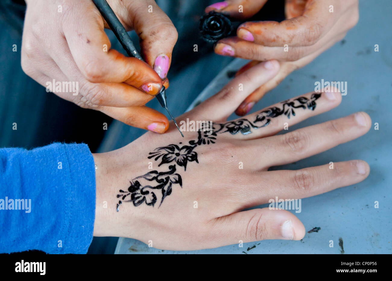 Street artist apply black henna on customer's skin. Stock Photo