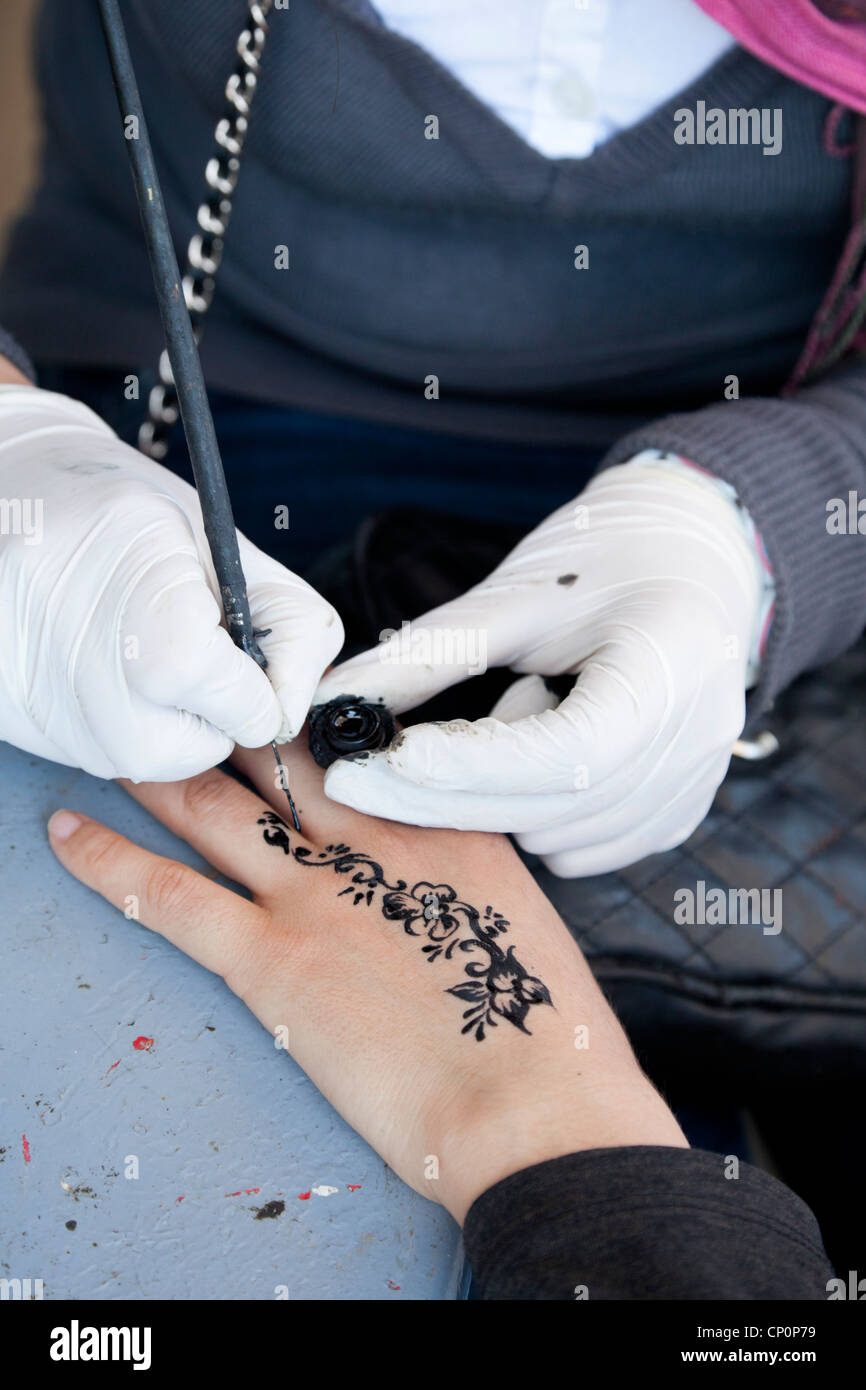 Street artist apply black henna on customer's skin. Stock Photo