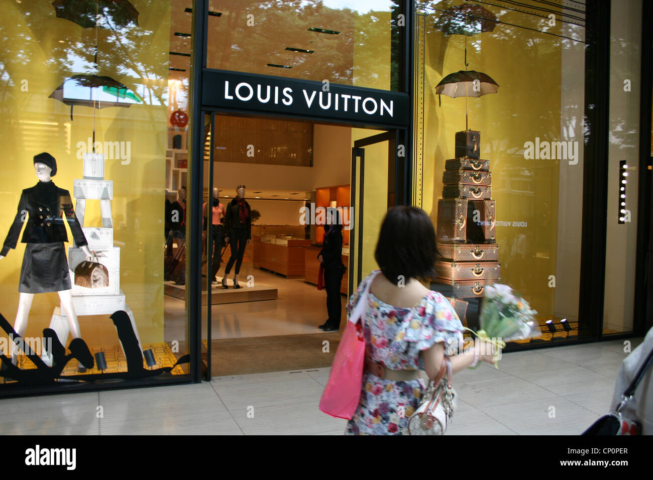 A woman walks by the Louis Vuitton shop and looks inside, Tokyo Japan ...