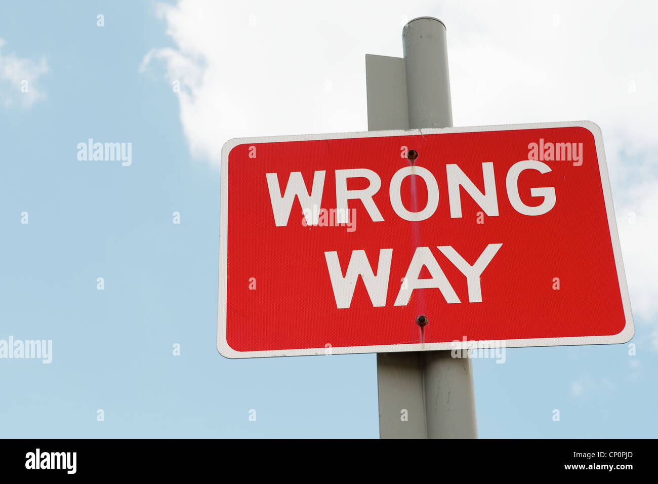 Wrong Way sign post against a cloudy blue sky.  Can be used as a metaphor for poor business or personal decisions Stock Photo