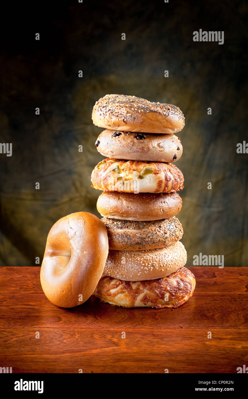 A stack of assorted, fresh, flavorful bagels on a deep, rich redwood table. Stock Photo