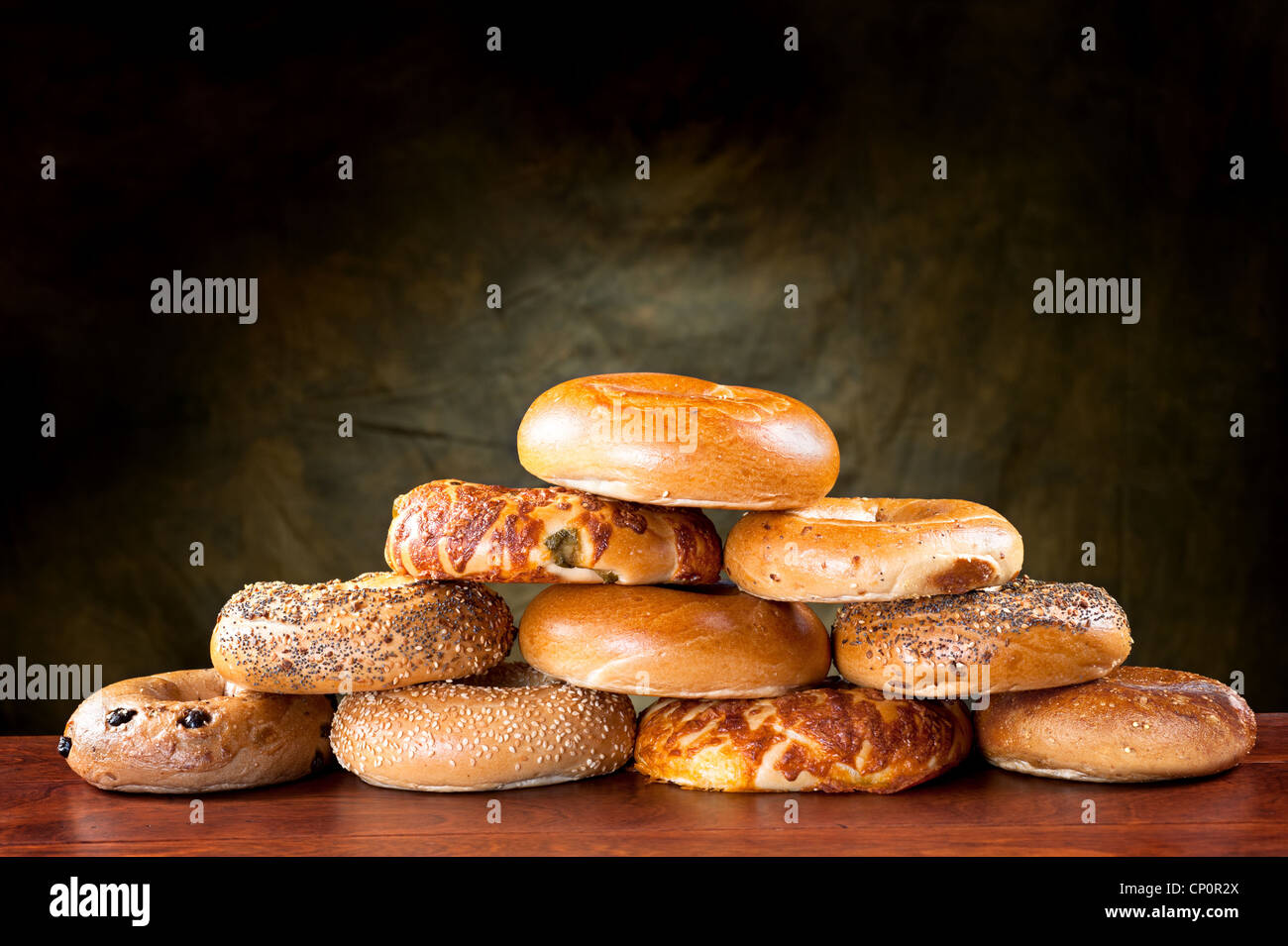 An assortment of flavored, seasoned breakfast bagels against a moody, green backdrop. Stock Photo