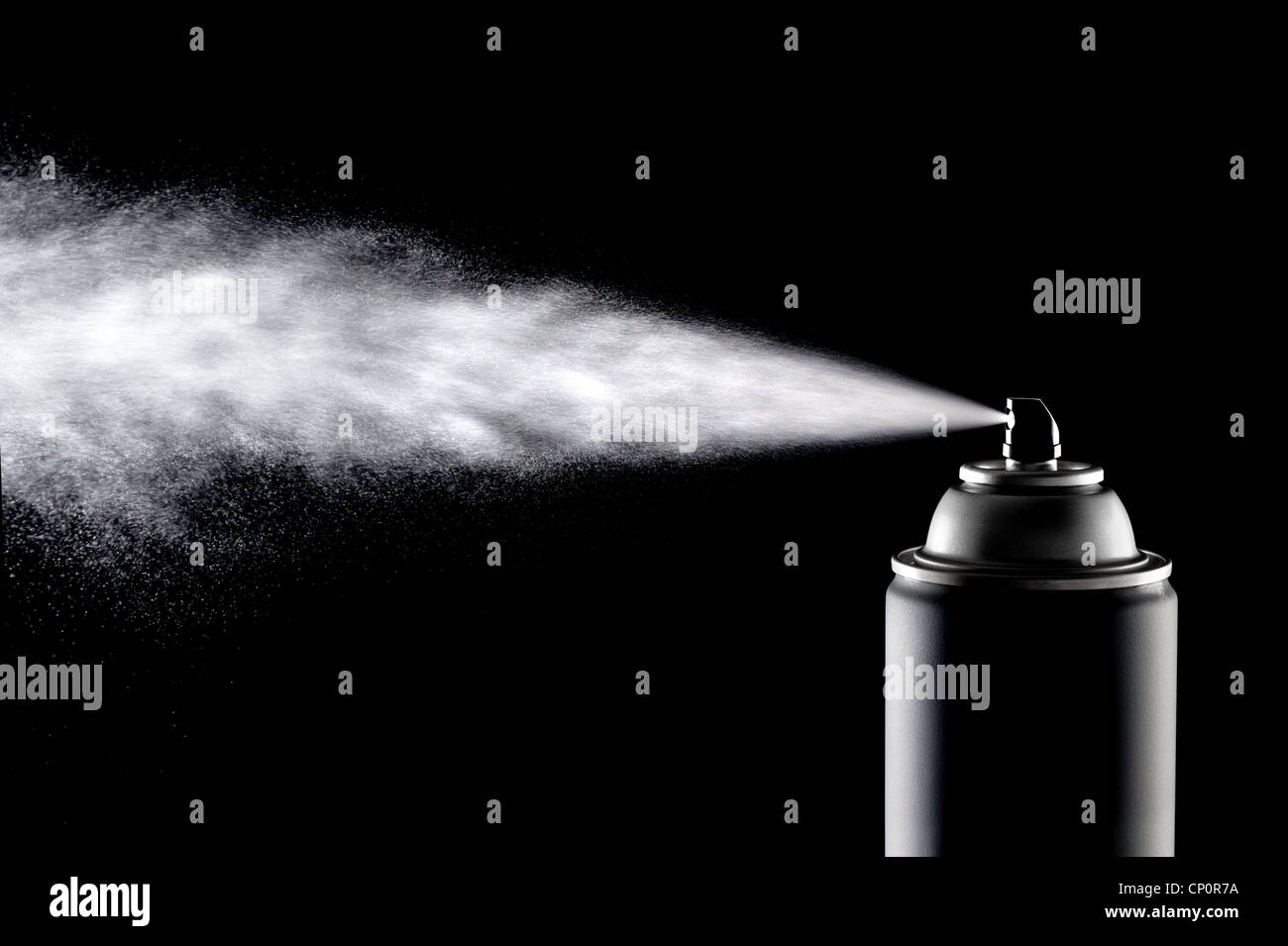 An aerosol can of spray dispensing its content against a backlit black background. Stock Photo