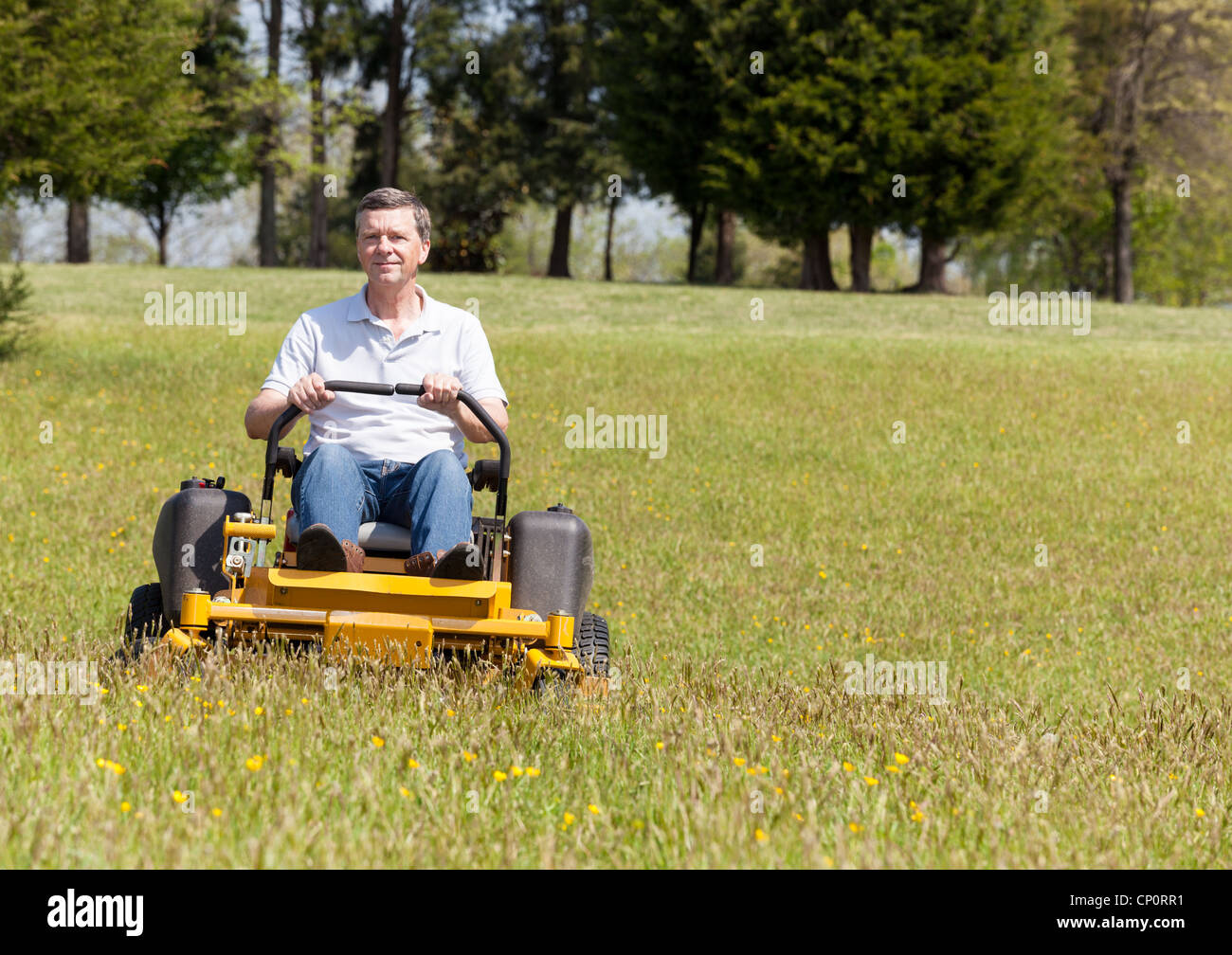 Senior retired male mowing the lawn and cutting the grass on a sit-on lawn mower Stock Photo