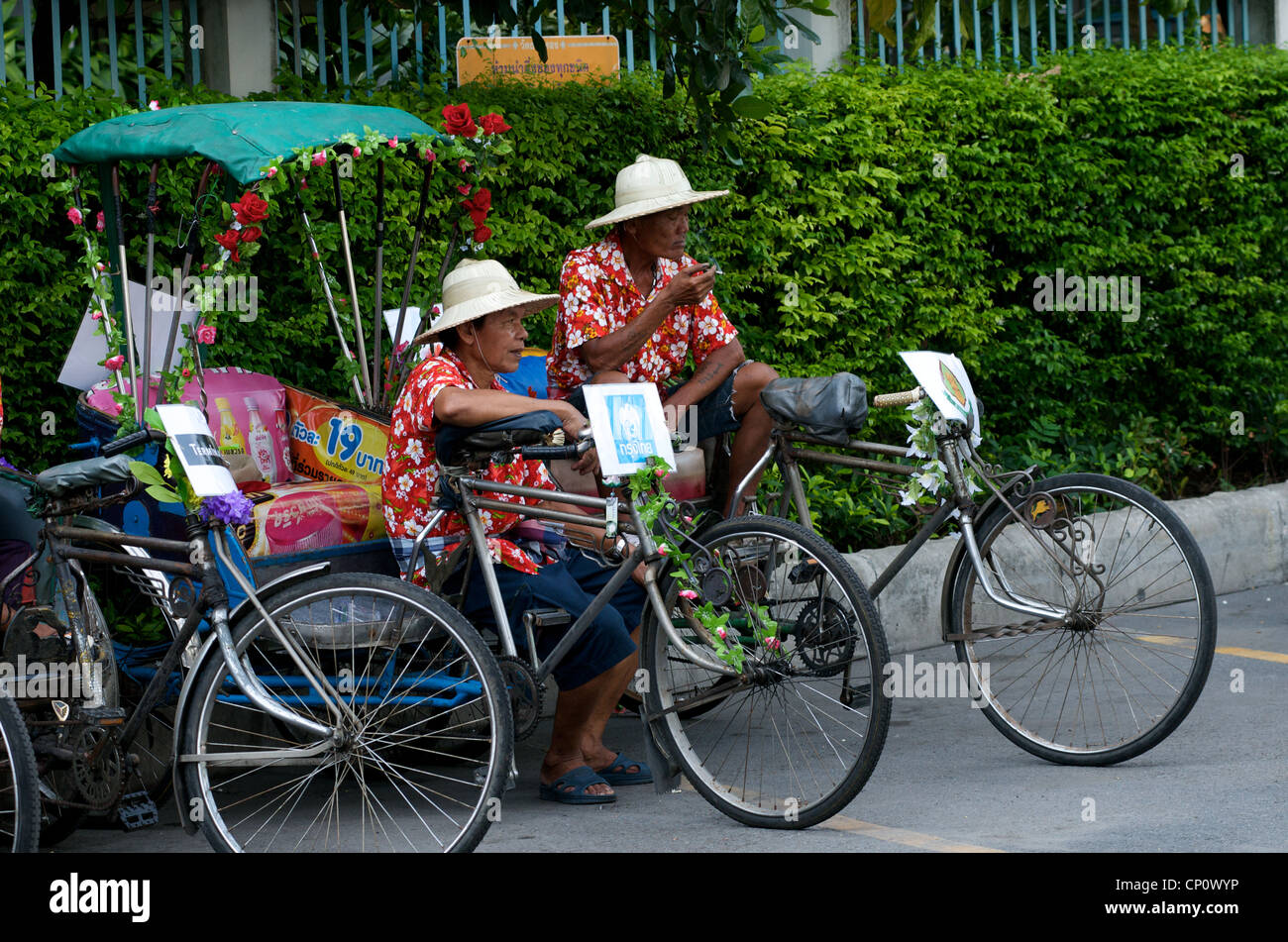 cyclo or bicycle rickshaw drivers take a brake during The Thai New Year celebration on Sukhumvit Road, Bangkok, Thailand. Stock Photo