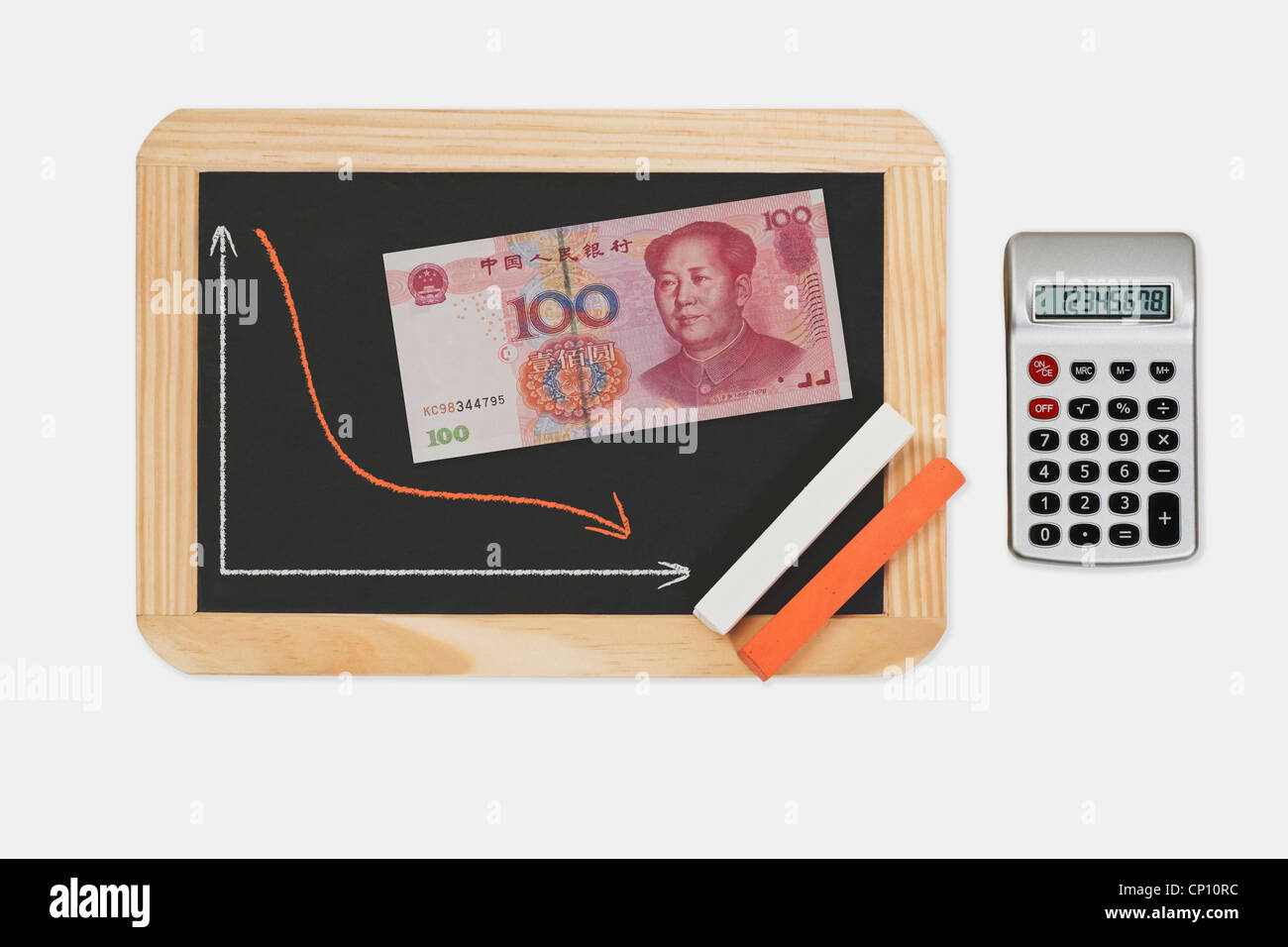 Chalkboard, chart with an declined curve. On the chalkboard lies a Chinese 100 Yuan banknote with the portrait of Mao Zedong. Stock Photo