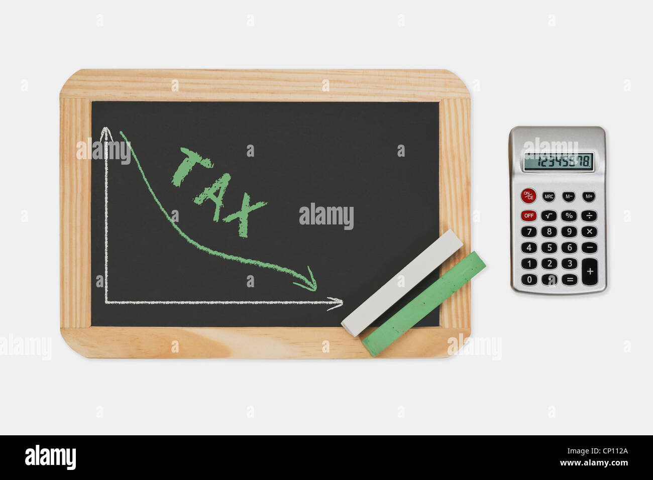 Chalkboard, a chart with an declined curve. On the chalkboard is the word Tax written. Pocket calculator at the right side. Stock Photo