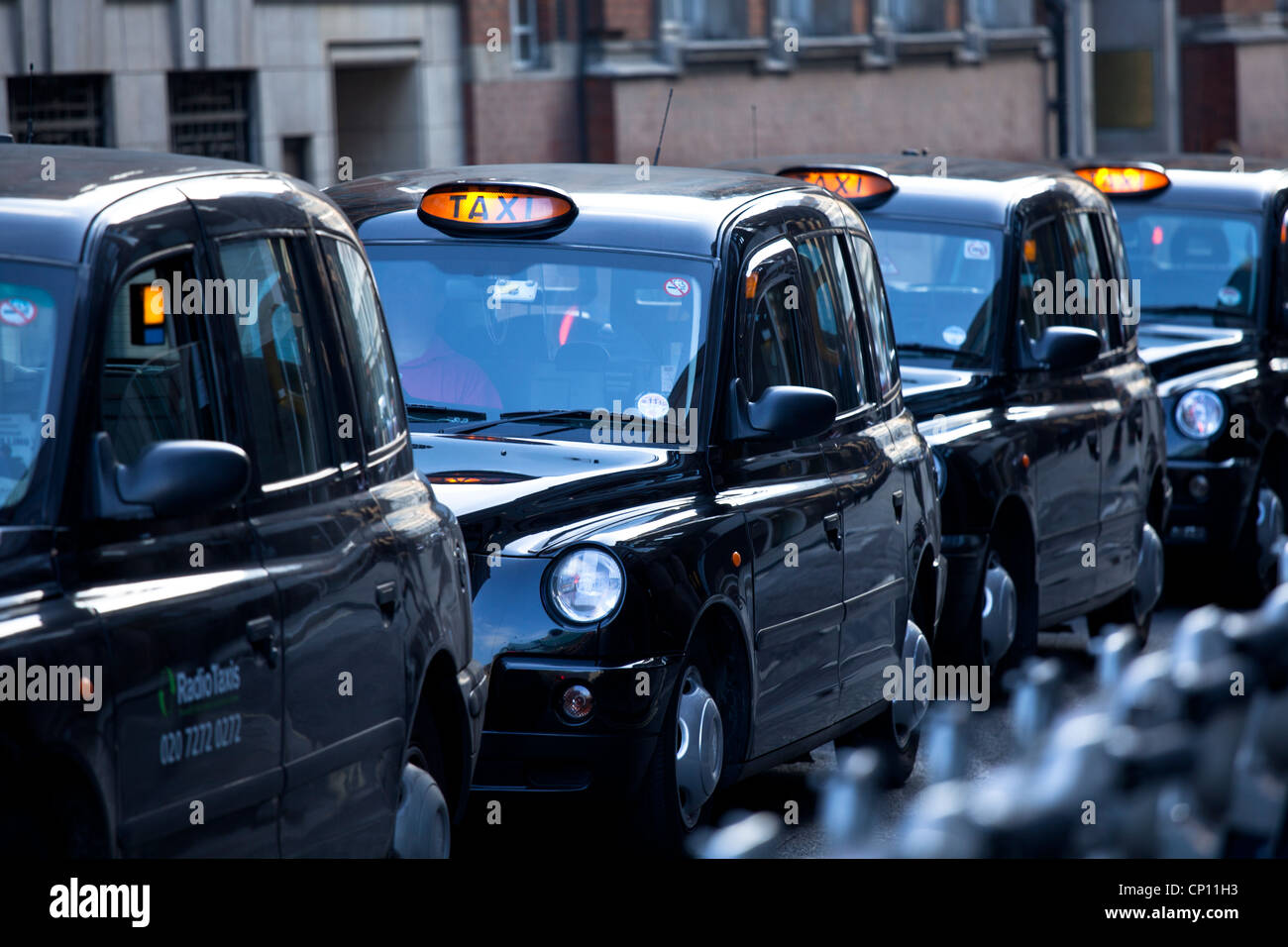 A line of black London taxy cabs waiting at traffic lights in Central London Stock Photo