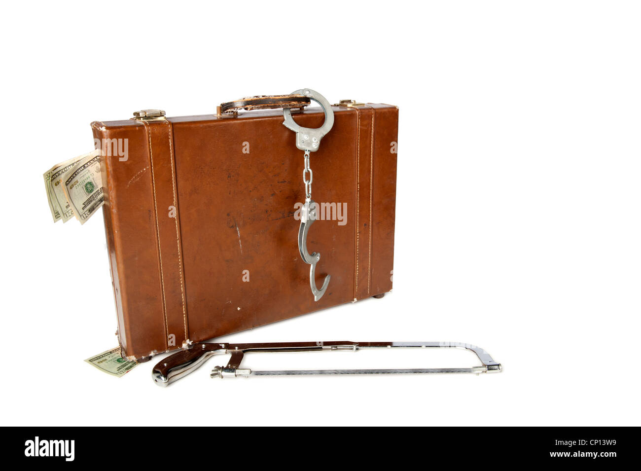 A hacksaw lies beside a leather briefcase with handcuffs on the handle and cash sticking out of it Stock Photo
