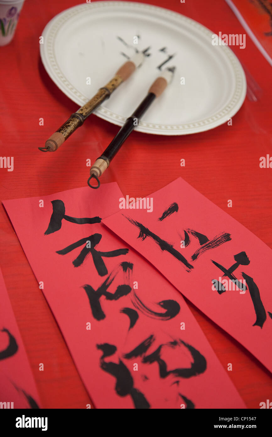 Freshly written Chinese calligraphy using black ink and bamboo brushes on red paper. Stock Photo
