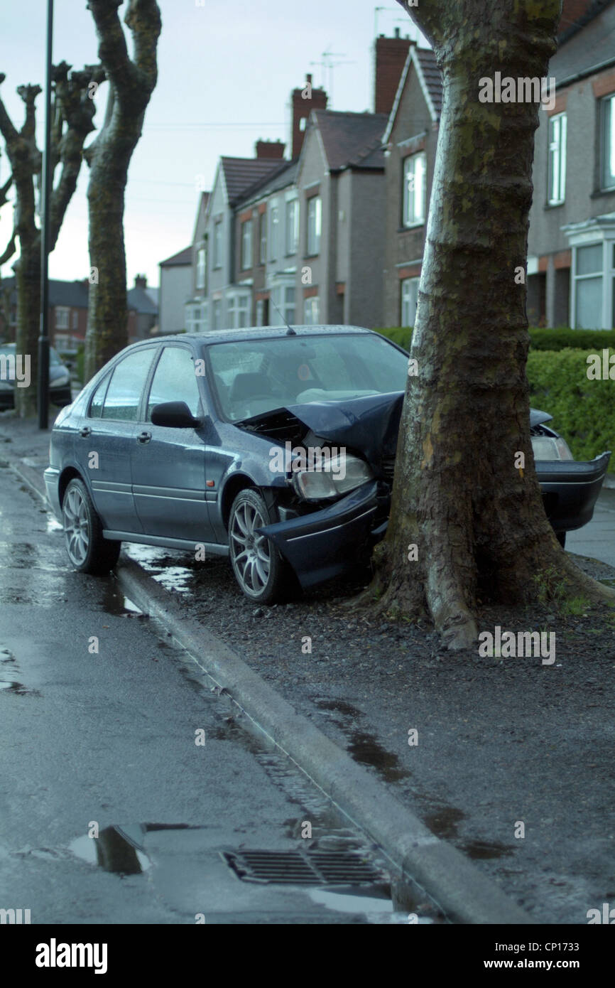 Road traffic accident in the rain. Car hits tree on busy main road in