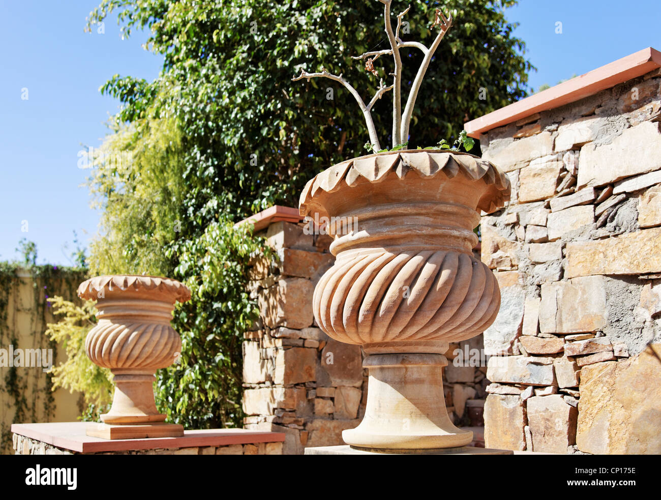 Generic garden featuring stone carved plant pots amd randon local stone masoned wall Stock Photo