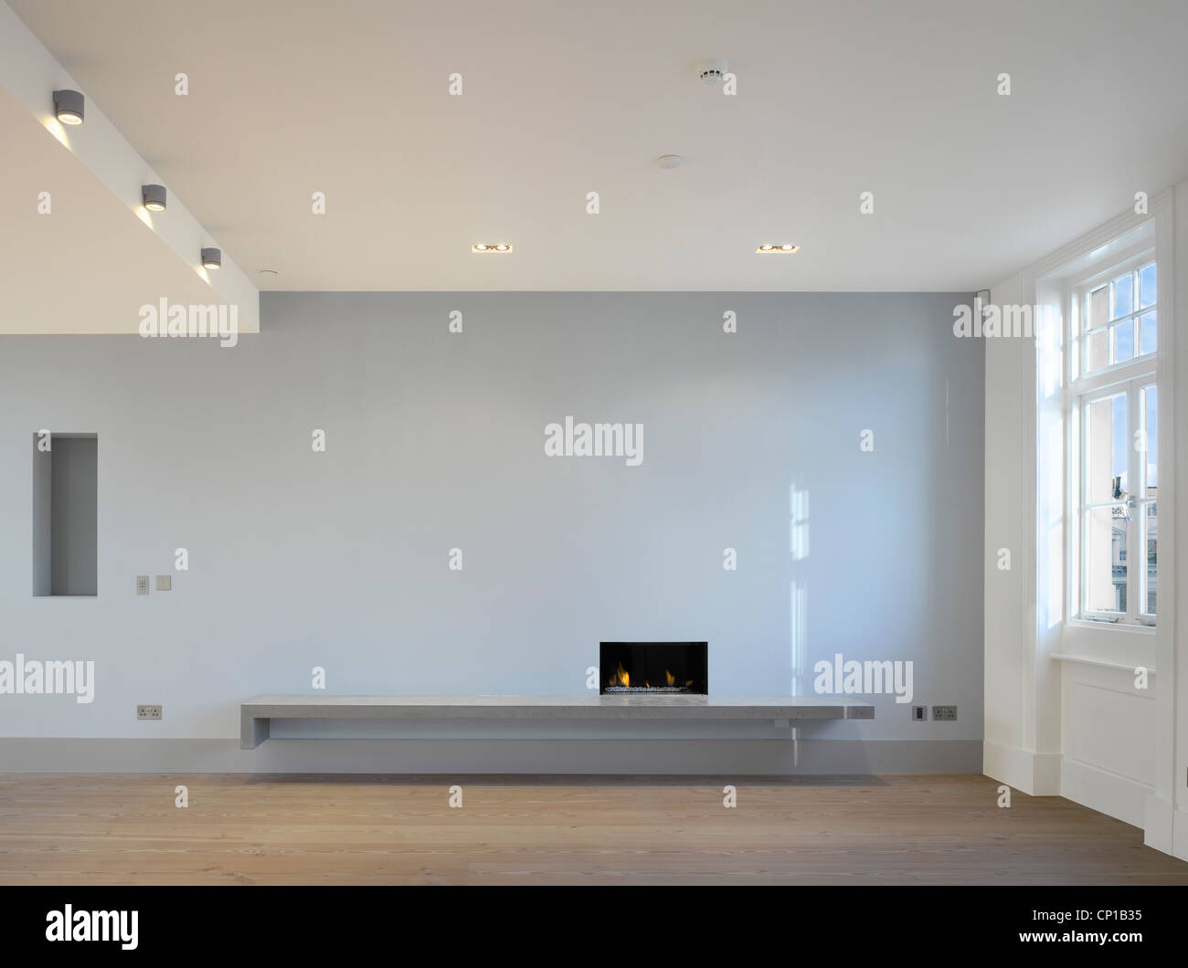 Open plan living room with fireplace, downlighters and wooden floor by Paul Archer Design
