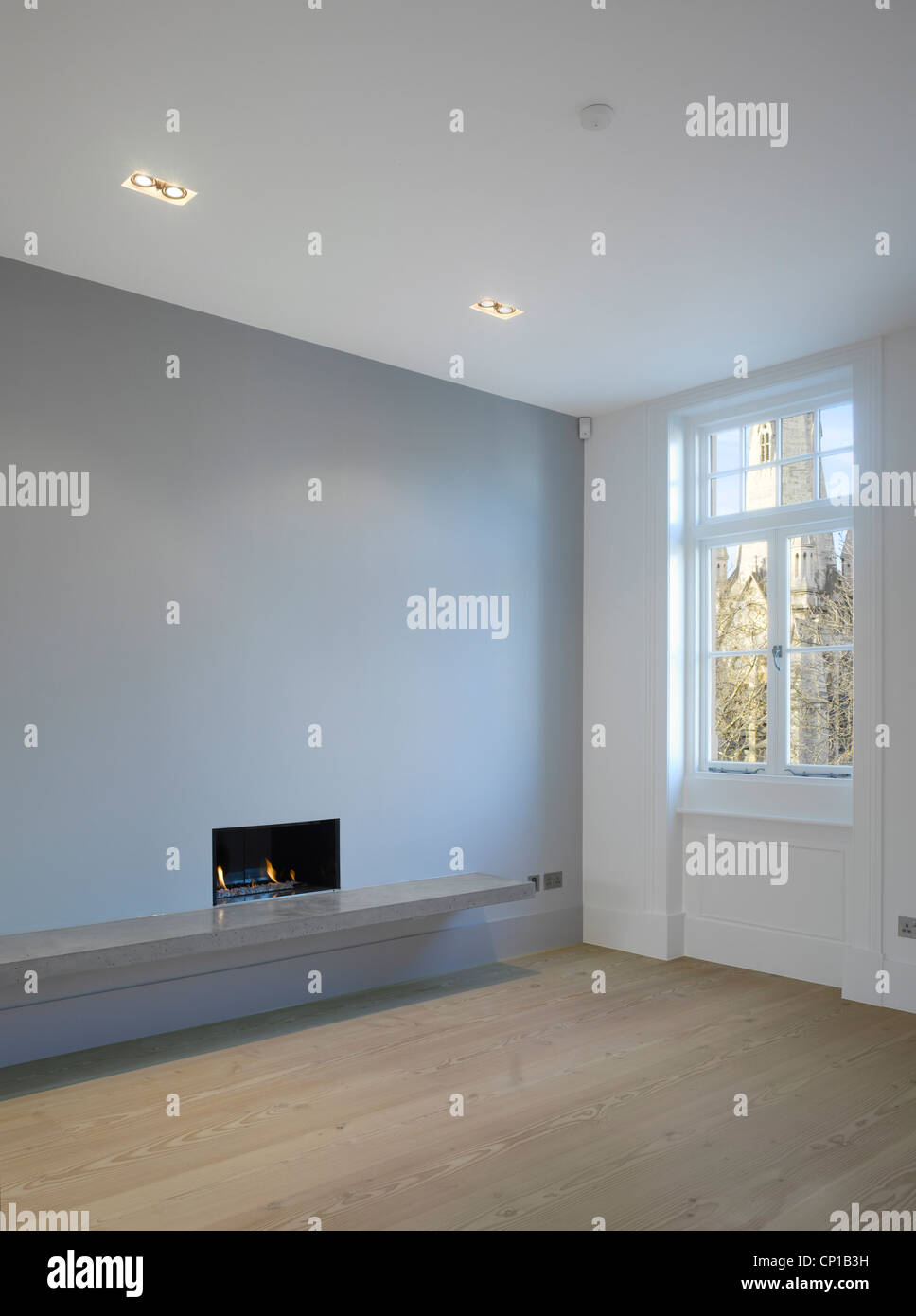 Open plan living room with fireplace, downlighters and wooden floor in empty flat Stock Photo