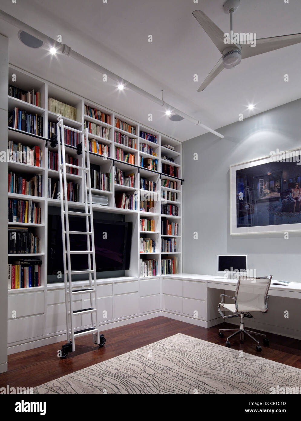 Built-in shelving in home office with mobile ladder and Gregory Crewdson print on the wall. New York, USA. Stock Photo