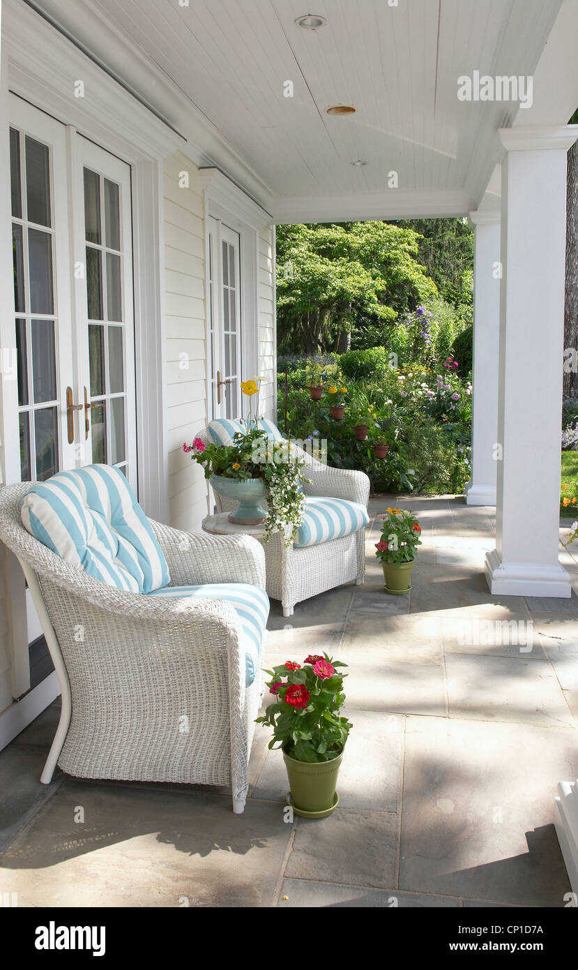 Wicker chairs with blue and white stripe cushions on house veranda Stock Photo