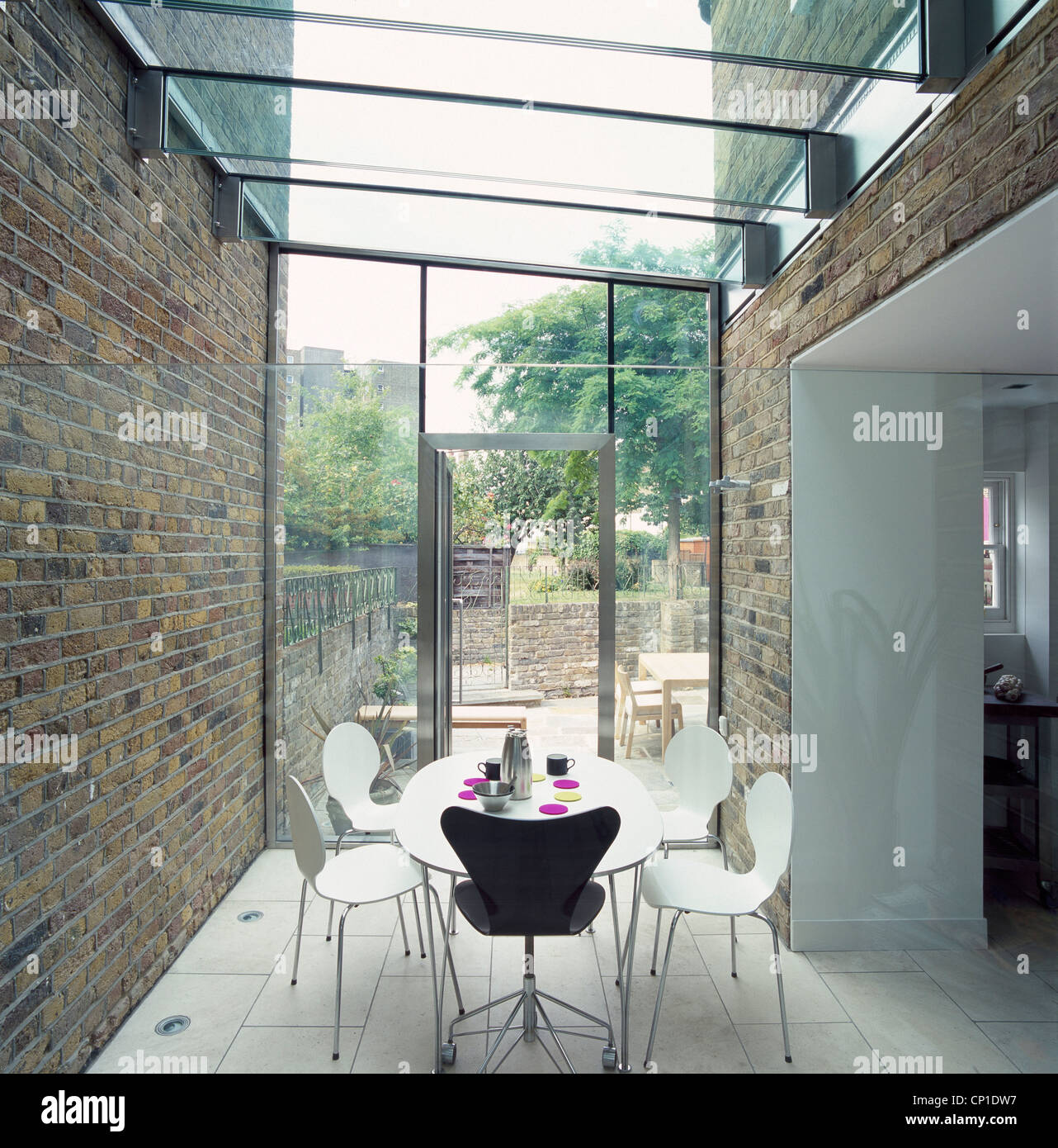A modern dining room in a glass conservatory extension, circular table and chairs Stock Photo