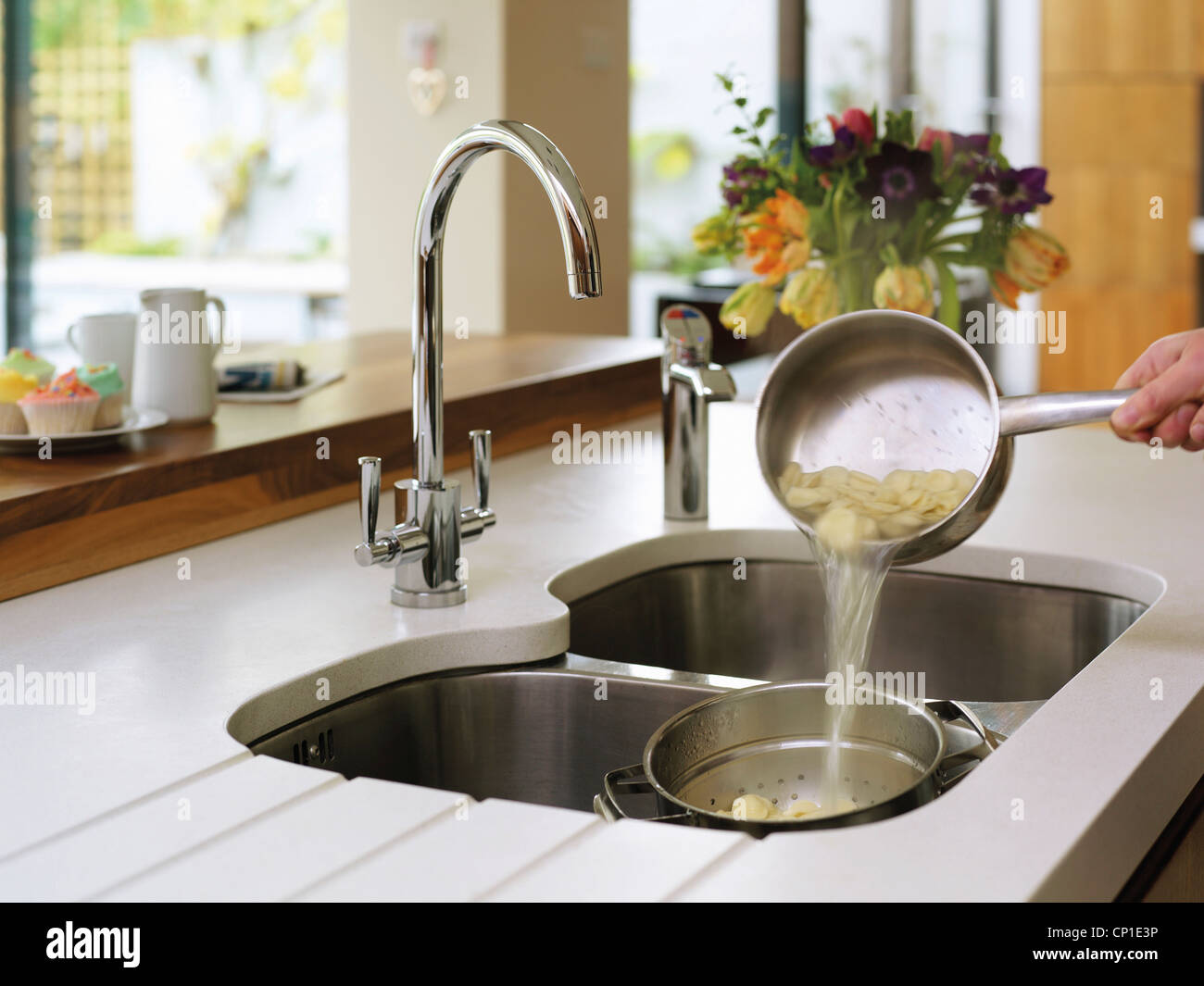 Person draining pasta in kitchen sink Stock Photo Alamy