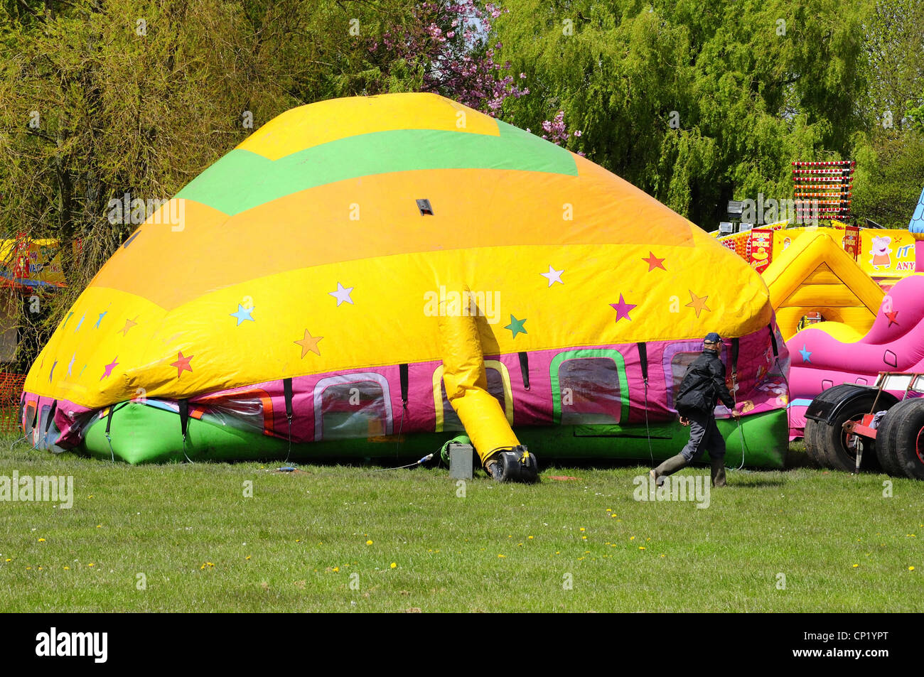 'Jump and Smile' inflatable house bouncy castle type attraction being inflated before fair opening in Debdale Park, Gorton Stock Photo
