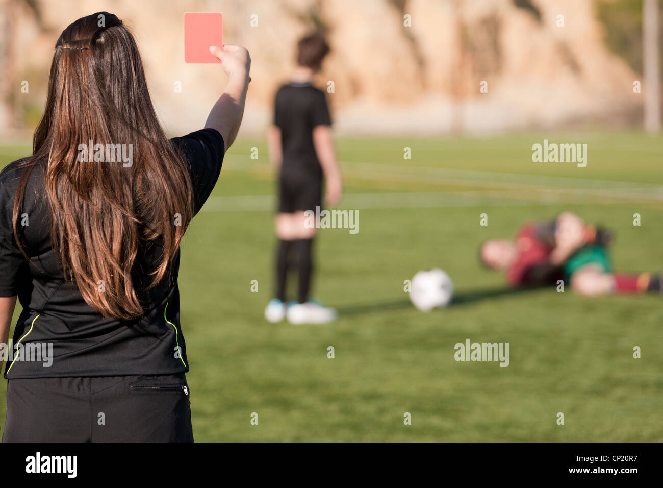 female referee showing the red card to the player with a injured player on the field Stock Photo