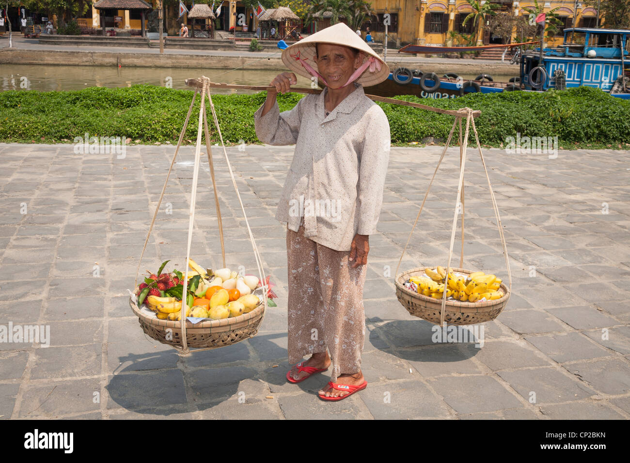 A Vietnamese woman, carrying baskets of fruit, Hoi An, Quang Nam province, Vietnam Stock Photo