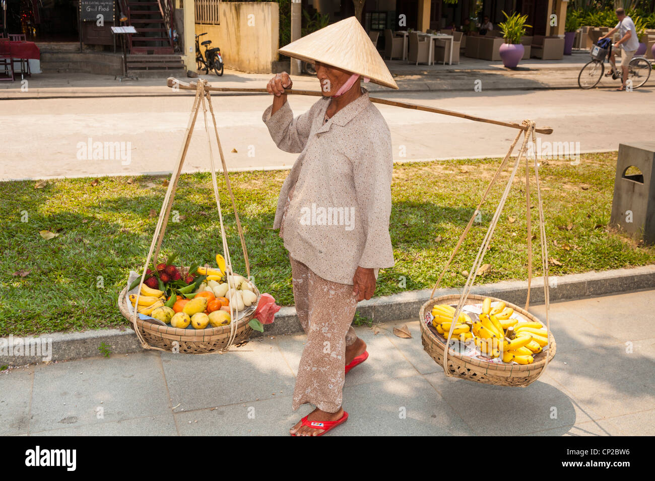 A Vietnamese woman, carrying baskets of fruit, Hoi An, Quang Nam province, Vietnam Stock Photo